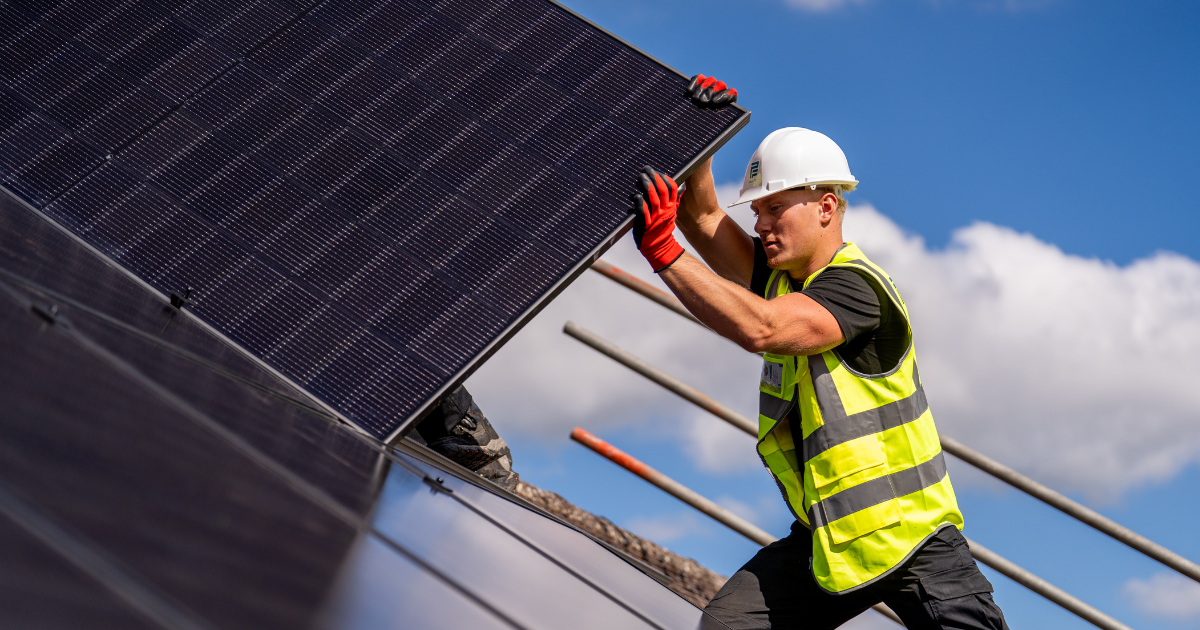 A Pro-Fit installer lifting a solar panel into position on a domestic roof
